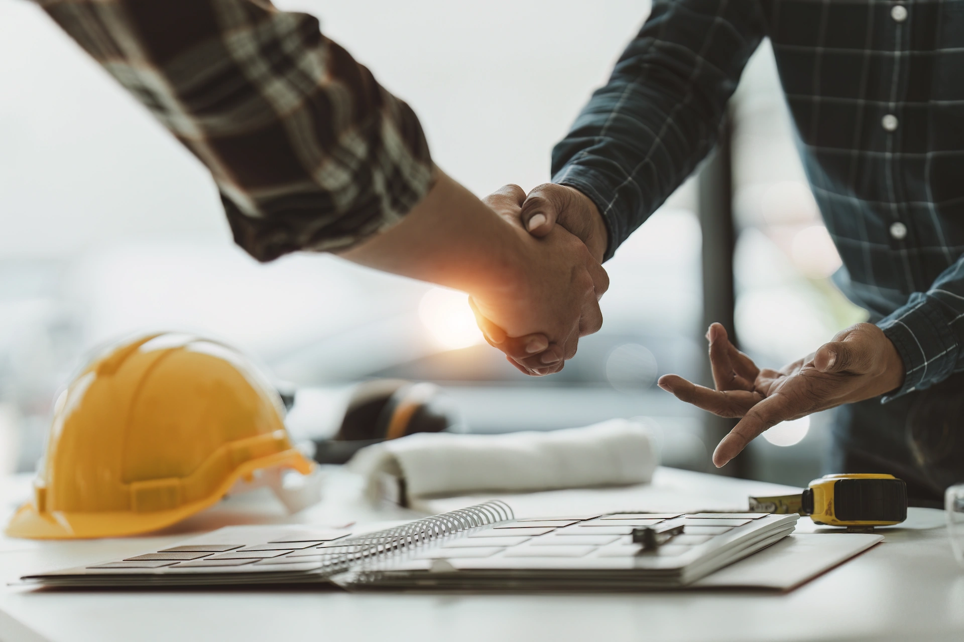 2 people shaking hands over a project plan
