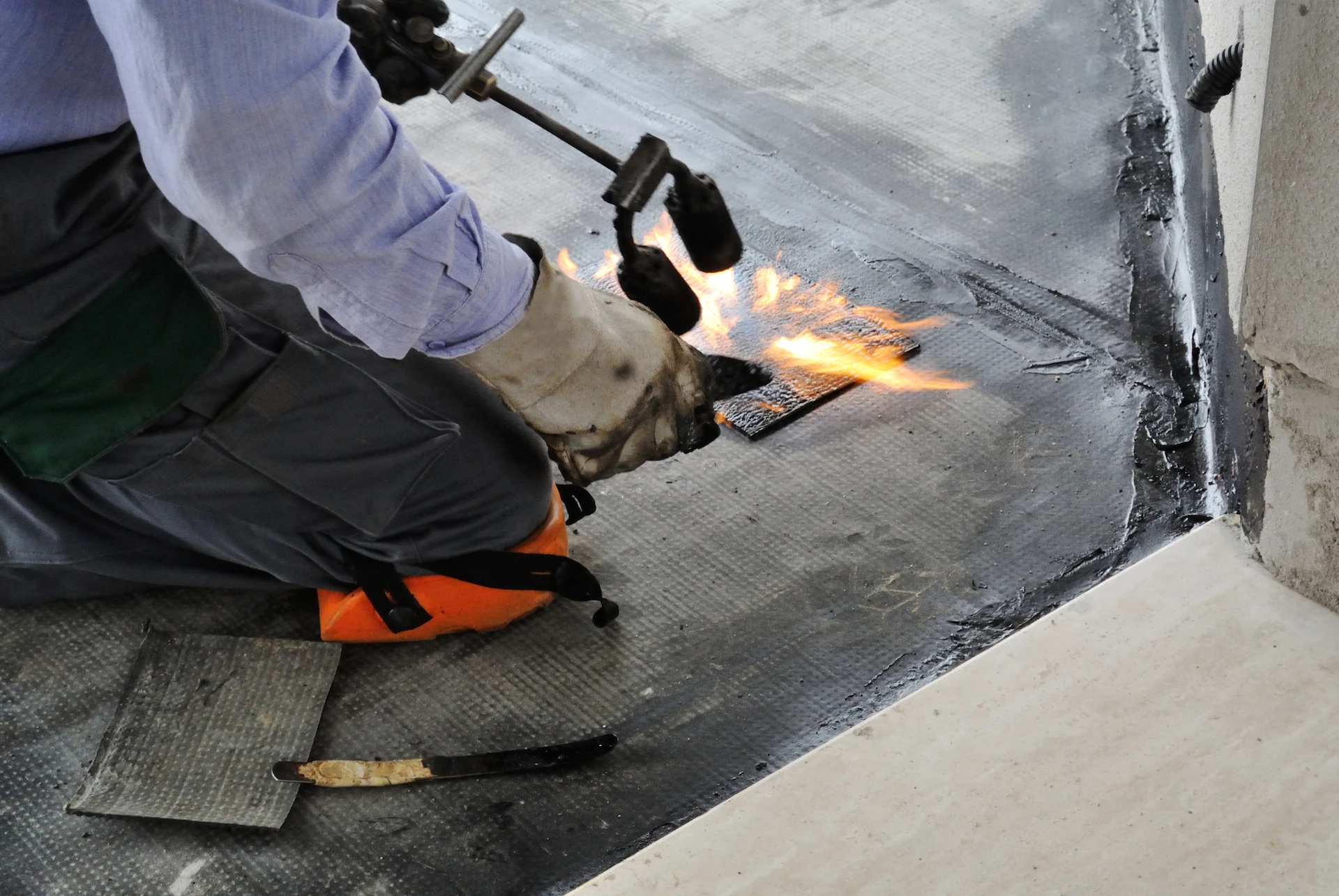 roof worker using a blowtorch to heat sealant