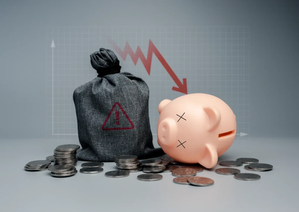 bag of money with alert symbol on it next to a tipped over piggy bank