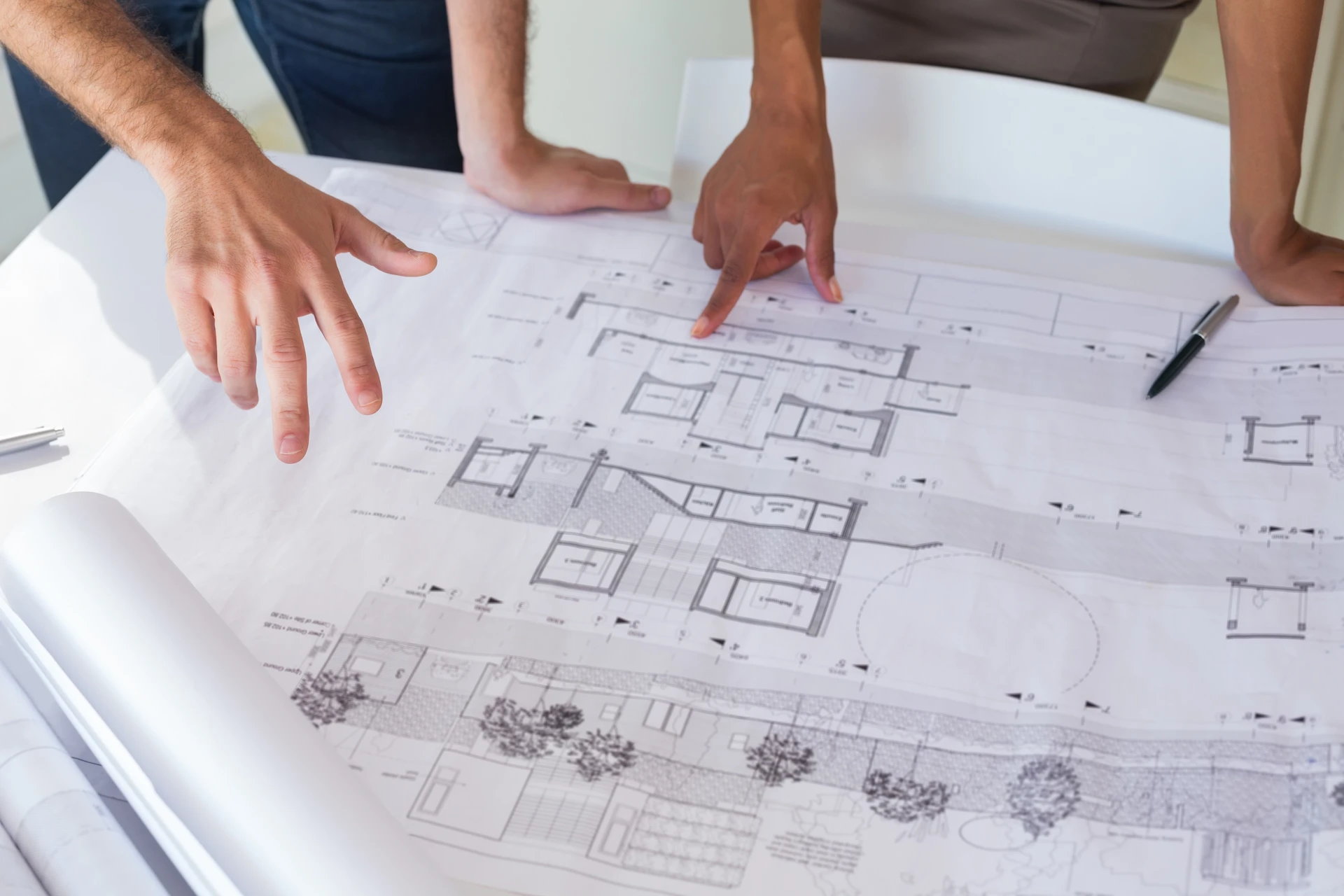 contractors looking at building blueprints sprawled out on a desk
